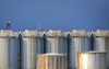 Cameroon, Douala: silos connected by a conveyor belt at the harbor - two oil tanks in the foreground - the conveyor belts is supported by one element trusses - photo by M.Torres