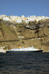 Greece, Cyclades, Santorini: view of Fira on the clifftops while a small cruise ship lies at anchorin the caldera - photo by P.Hellander