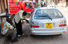 Cape Maclear / Chembe, Malawi: fueling a car with a bottle of black market gasoline, the only kind available - Coca-Cola truck in the background - Toyota Corolla - photo by M.Torres